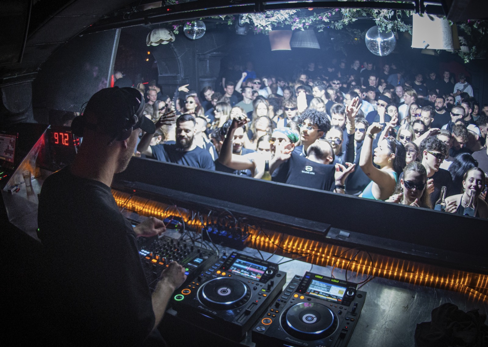 DJ booth facing an energetic nightclub crowd